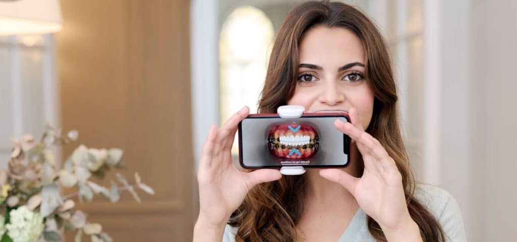 woman scanning her teeth with phone using dental monitoring app